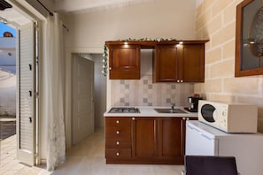 A compact kitchen with wooden cabinets, a microwave, and a gas stove. - 2933 Villetta Patrizia - Monolocale by Barbarhouse (Manduria)