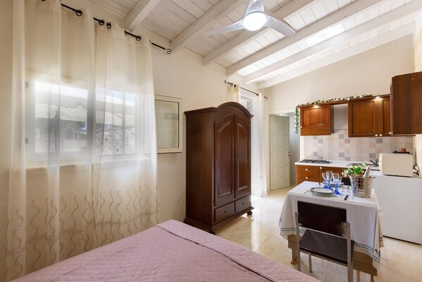 A bedroom with a bed, a wardrobe, and a dining area with a table set for two.