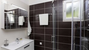 A modern bathroom with a glass-enclosed shower, a white sink, and a mirror above it. - Apartments Posta (Mljet)