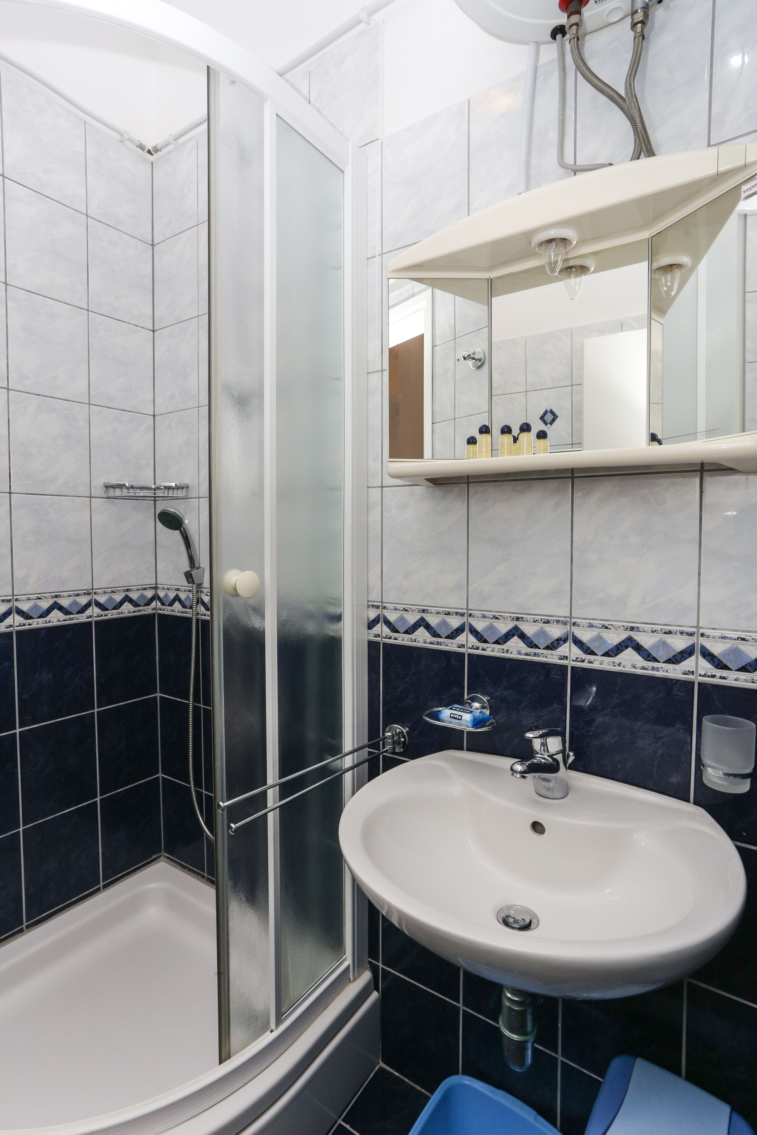A bathroom with a glass-enclosed shower, a white sink, and a mirror above it.