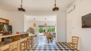 A modern kitchen with a checkered floor, wooden bar stools, and a large window overlooking a garden.
