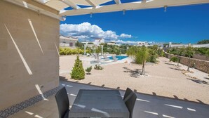 A covered patio with a table and chairs, a swimming pool, and a view of the surrounding neighborhood. - 2494 Villa Tina Maria by Perle di Puglia (Manduria)
