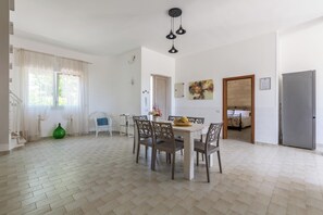 Ein geräumiger Wohnbereich mit Esstisch, Stühlen, einer Couch und einem Kühlschrank.