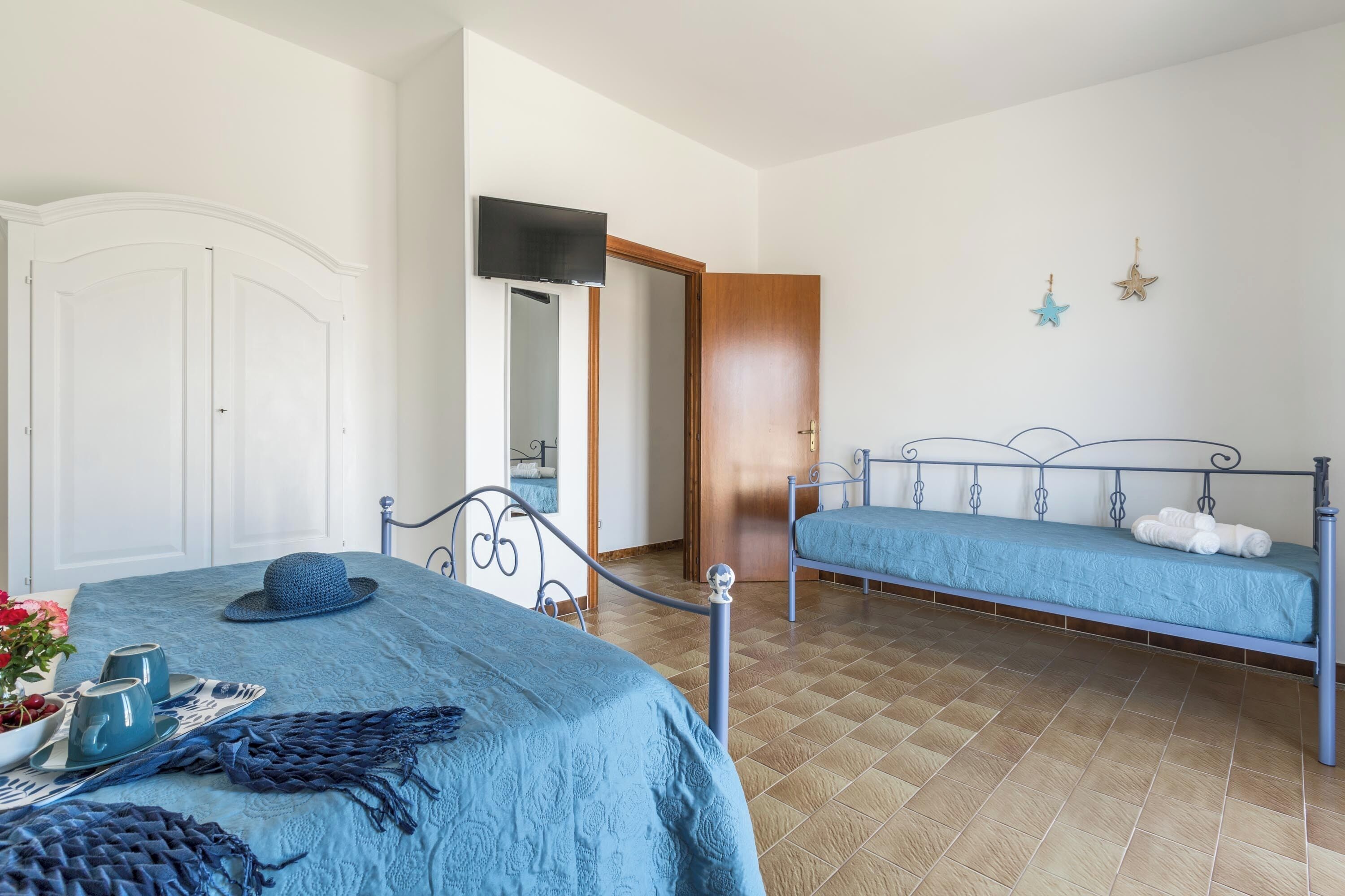 A bedroom with a bed, a bedside table, a chair, a wardrobe, and a mirror.