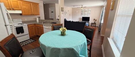 A compact kitchen with a dining area, wooden cabinets, a stove, and a dining table with chairs.