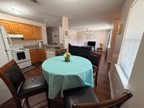 A compact kitchen with a dining area, wooden cabinets, a stove, and a dining table with chairs.