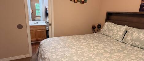 Une chambre à coucher comprenant un lit, une commode, une coiffeuse avec un miroir et une porte donnant sur une autre pièce.