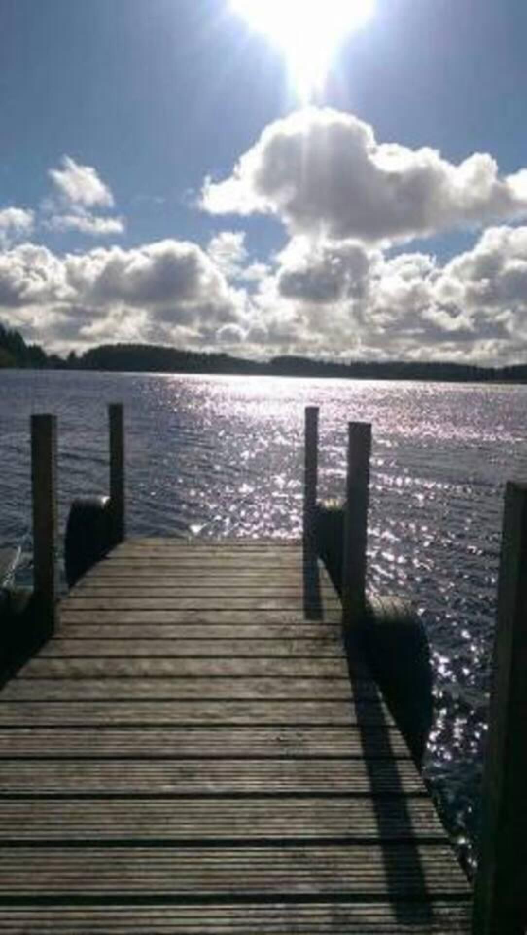 Une jetée en bois s’étendant sur une étendue d’eau, sous un ciel dégagé.