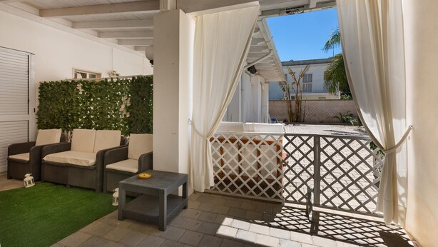 A covered patio area with outdoor furniture, a small table, and a white curtain. - 2934 Villetta Patrizia - Bilocale by Barbarhouse (Manduria)