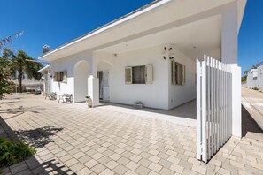 A white building with a covered patio, a white fence, and a clear blue sky. - 2934 Villetta Patrizia - Bilocale by Barbarhouse (Manduria)