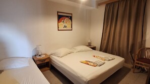 Una habitación de hotel con cama, mesita de noche, lámpara y un cuadro en la pared.
