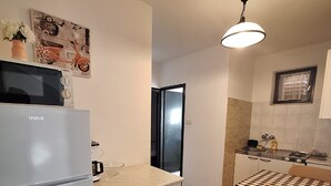 Una cocina compacta con refrigerador, microondas, lavamanos y comedor con mesa y sillas.