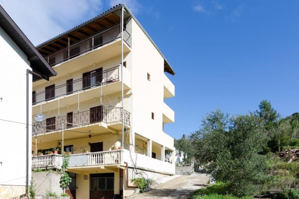 Un edificio de varios pisos con balcones, techo plano y cielo despejado.