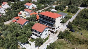 Vista aérea de una zona residencial con varias casas de dos pisos, cada una con techos de tejas rojas, rodeadas de vegetación.