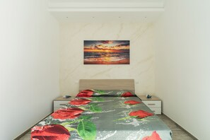 A bedroom with a bed, a nightstand, a drawer, and a painting of a sunset on the wall. - 2805 Villetta Anna by Barbarhouse (Porto Cesareo)