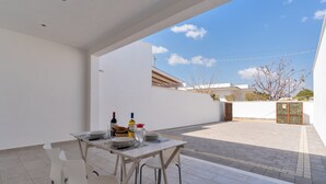 A patio with a table set for dining, outdoor chairs, and a view of neighboring buildings. - 2805 Villetta Anna by Barbarhouse (Porto Cesareo)