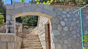 A stone staircase leading to a door, surrounded by stone walls and a small lamp post. - Guest House Hazdovac Rooms (Mljet)