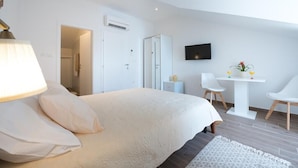 A modern bedroom with a large bed, a bedside table, a TV, and a small desk with chairs.