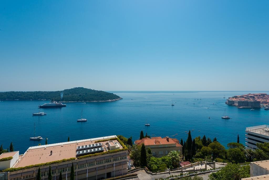Un paysage urbain côtier offrant une vue dégagée sur la mer, avec plusieurs bateaux et des bâtiments dont l’architecture combine des éléments modernes et traditionnels.