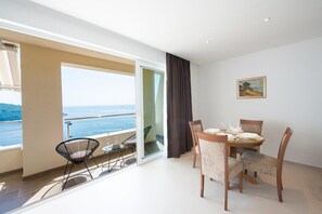 Enjoy a panoramic sea view from the balcony, featuring a dining area with a round table and chairs.