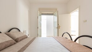 Ein Schlafzimmer mit einem Bett, einem Nachttisch und einer Tür zu einem anderen Raum.