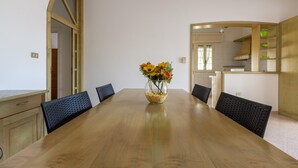 Ein Essbereich mit einem Holztisch, sechs Stühlen und einer Blumenvase.