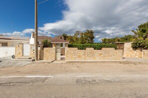 A residential area with a stone wall, a gate, and a building with a tiled roof. - 2401 Villetta Rosa by Barbarhouse (Maruggio)