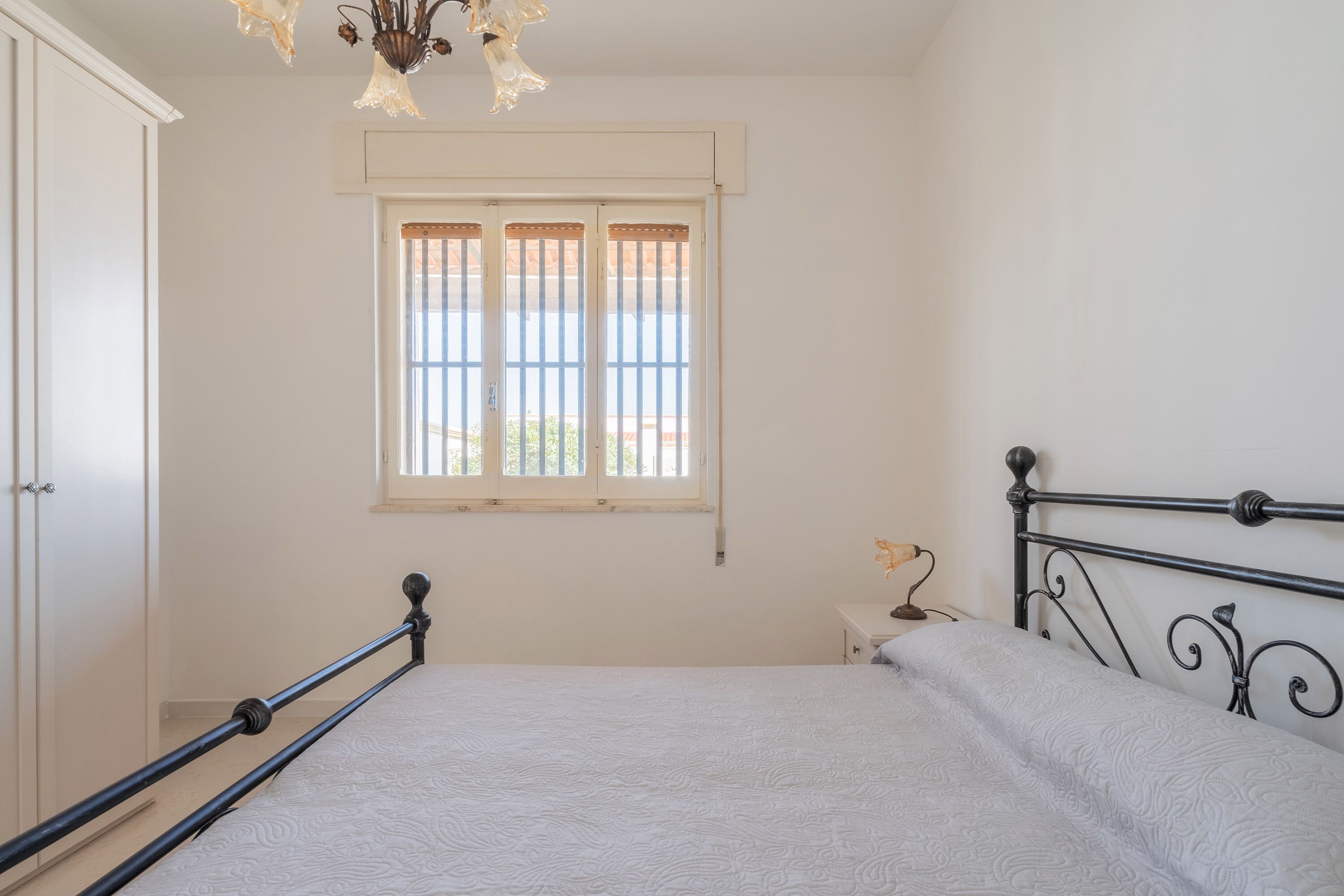 A bedroom with a bed, a window, and a nightstand.
