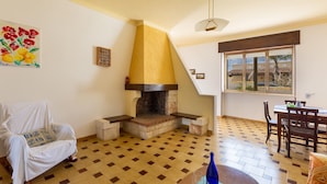 A cozy living room with a fireplace, a dining area, and a window with a view. - 2746 Villa Rosa di Mare by Barbarhouse (Porto Cesareo)