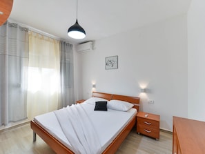 Une chambre bien rangée, avec un lit, des tables de chevet, un bureau et un luminaire suspendu.
