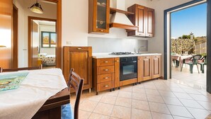 Una cocina moderna con armarios de madera, horno empotrado y zona de comedor con mesa y sillas.