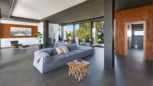 A spacious living area with a grey sofa, a wooden coffee table, and a dining area with chairs and a table. - 3127 Villa Ottavia by Perle di Puglia (Porto Cesareo)