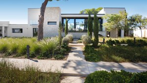 A modern house with a pathway leading to the entrance, surrounded by greenery and trees. - 3127 Villa Ottavia by Perle di Puglia (Porto Cesareo)
