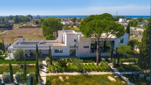 A modern two-story house with a flat roof, surrounded by lush greenery and a clear view of the sea. - 3127 Villa Ottavia by Perle di Puglia (Porto Cesareo)
