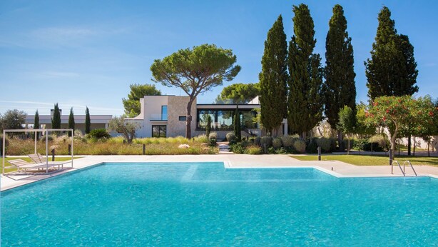 A swimming pool with a modern building in the background, surrounded by trees and greenery. - 3127 Villa Ottavia by Perle di Puglia (Porto Cesareo)