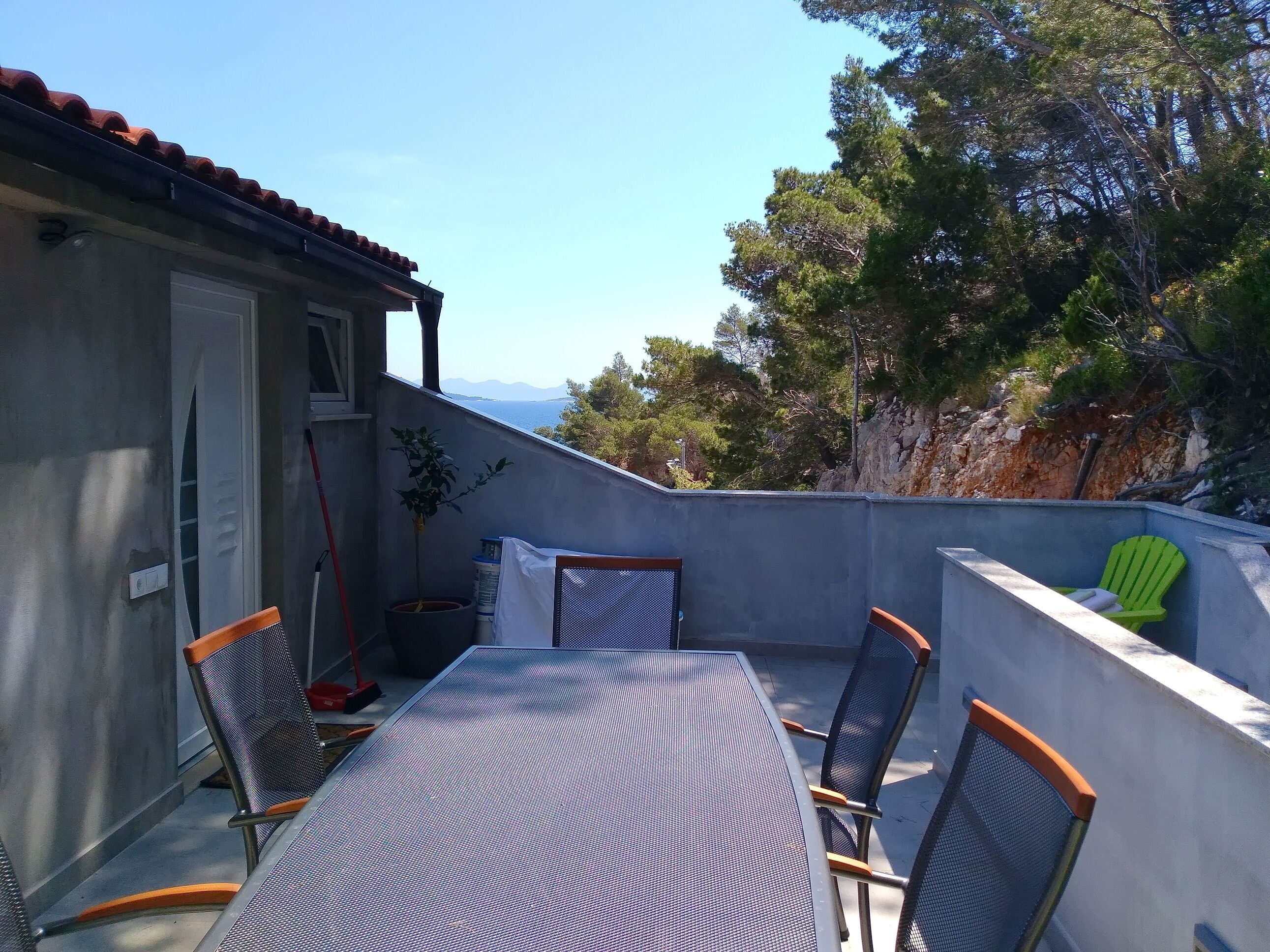Una terraza con mesa y sillas, una planta en maceta y vistas al mar y a las montañas.