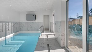 En modern inomhuspool med en fri utsikt mot himlen genom stora fönster.