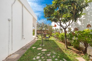 A narrow pathway with stepping stones leading to a small seating area surrounded by greenery and a white building. - 2961 Villa Poesia by Barbarhouse (Porto Cesareo)
