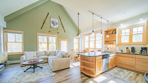 A spacious living area with a high ceiling, a dining table, and a kitchen with wooden cabinets and large windows. - Silver Mill 8244 (Keystone)