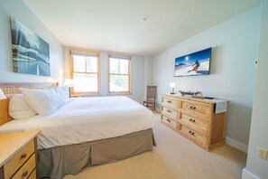 A bedroom with a large bed, a wooden dresser, two windows, and a painting on the wall. - Silver Mill 8244 (Keystone)