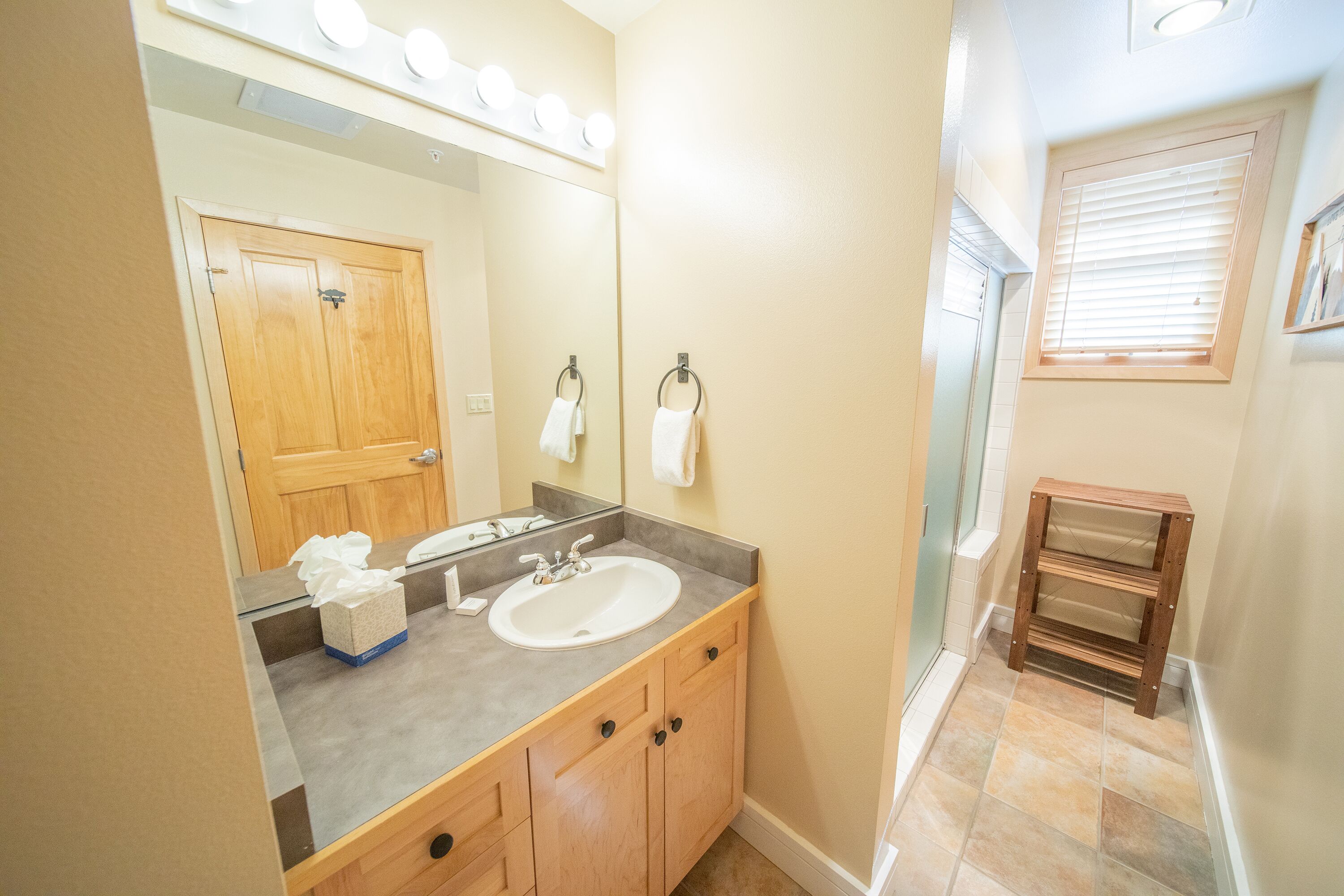 A bathroom with a sink, mirror, and wooden cabinets.