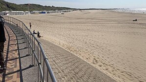 A beach with a paved walkway and a metal railing. - Beautiful 2-bed Apartment in Wenduine (De Haan)