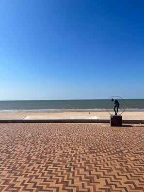 Ein Strand mit einem gemusterten Gehweg und einer Skulptur.