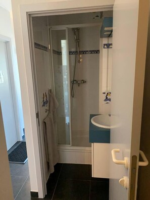 Ein Badezimmer mit einer Duschkabine, einem Waschbecken und einem Handtuchhalter.