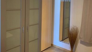 A room with a large wardrobe, a mirror, and a vase of dried plants. - Beautiful 2-bed Apartment in Wenduine (De Haan)