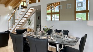 A dining area with a table set for four, a staircase, and large windows with a view of a mountainous landscape. - Impeccable 3-bed Duplex Penthouse in Saas-fee (Saas-Fee)