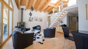 A spacious living area with a high wooden ceiling, a fireplace, and a staircase leading to an upper level. - Impeccable 3-bed Duplex Penthouse in Saas-fee (Saas-Fee)