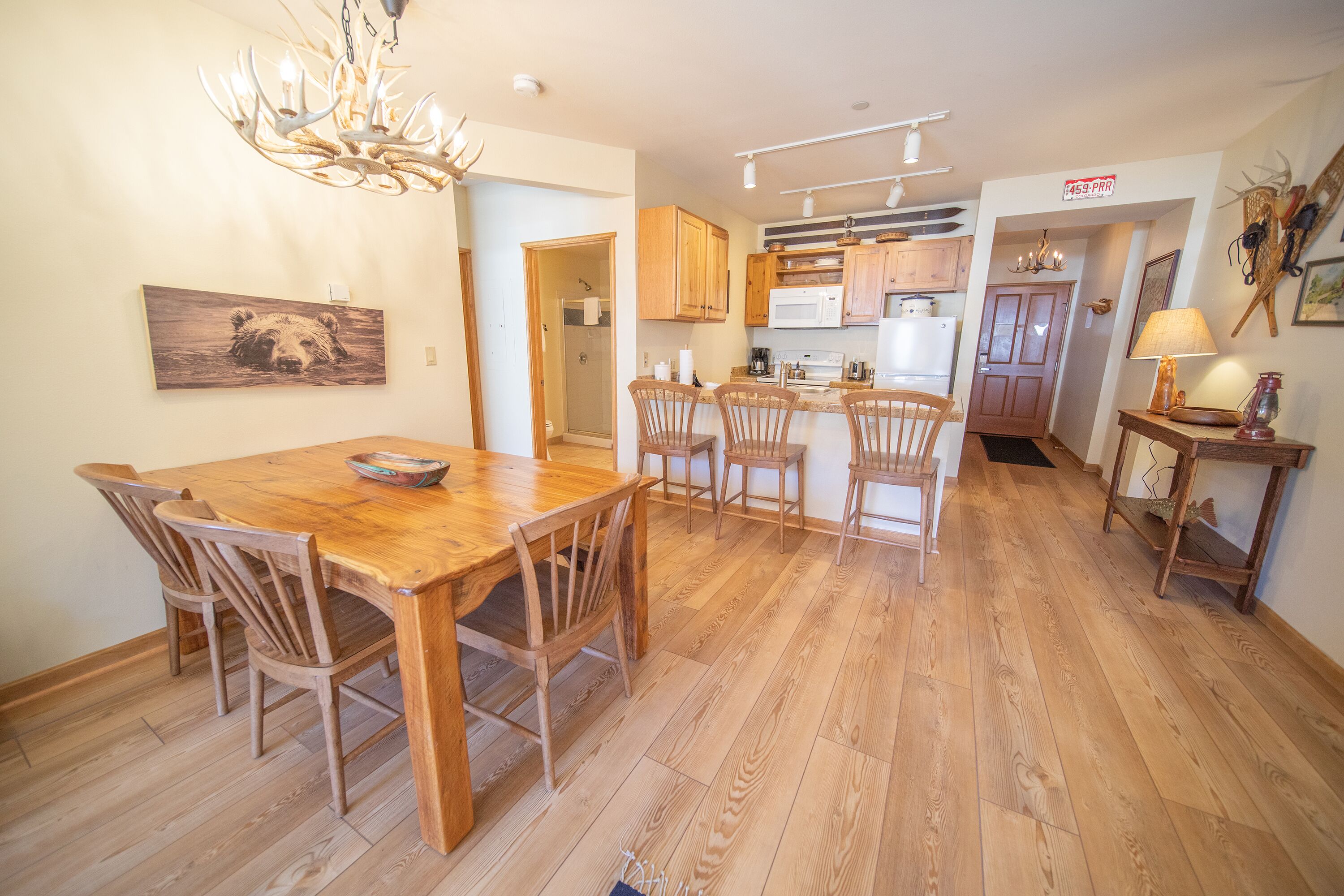 A spacious kitchen with wooden cabinets, a dining area with a wooden table and chairs, and a chandelier.