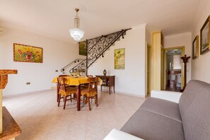 Uma área de jantar com uma mesa e cadeiras amarelas, uma escada com grades ornamentadas e um candelabro.