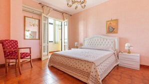 A bedroom with a large bed, a chair, a nightstand, and a chandelier. - 2348 Villino Mareluce by Barbarhouse (Porto Cesareo)